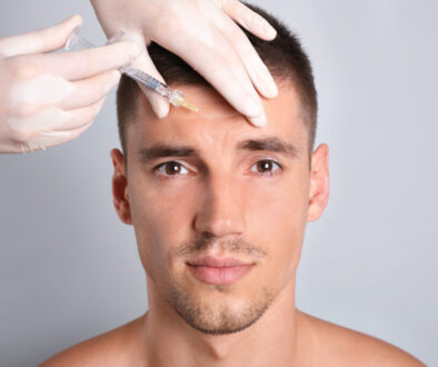 Man getting facial injection on grey background, closeup. Cosmetic surgery